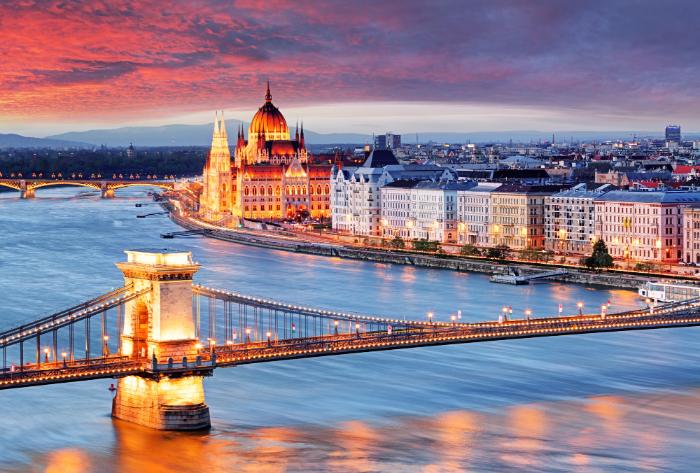 Scenic view of Budapest at sunset, featuring the illuminated Hungarian Parliament Building, the Chain Bridge, and the Danube River, a popular destination for dental tourism.